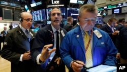 Traders Andrew Silverman, Gregory Rowe, and James Lamb, left to right work on the floor of the New York Stock Exchange, Aug. 15, 2019. 