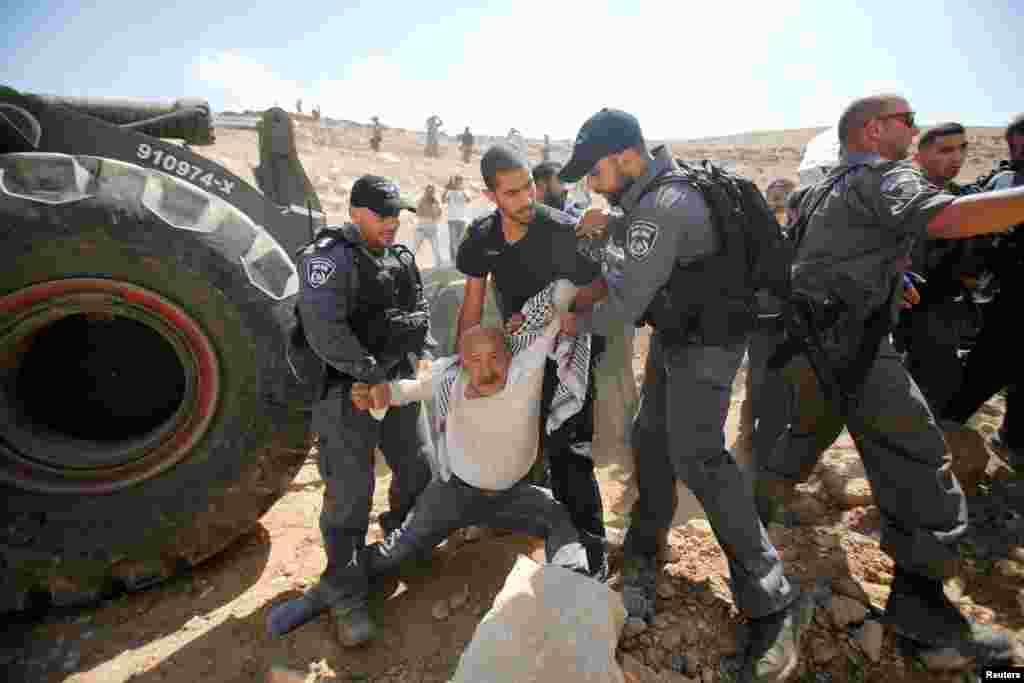 Israeli policemen detain a Palestinian as they protest against Israel's plan to demolish the Palestinian Bedouin village of Khan al-Ahmar, in the occupied West Bank.