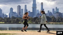 People exercise in front the city skyline in Melbourne on August 29, 2021, as authorites announced the extension of an ongoing coronavirus lockdown in Australia's second-biggest city. (Photo by William WEST / AFP)