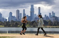 People exercise in front the city skyline in Melbourne on August 29, 2021, as authorites announced the extension of an ongoing coronavirus lockdown in Australia's second-biggest city. (Photo by William WEST / AFP)