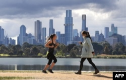 People exercise in front the city skyline in Melbourne on August 29, 2021, as authorites announced the extension of an ongoing coronavirus lockdown in Australia's second-biggest city. (Photo by William WEST / AFP)