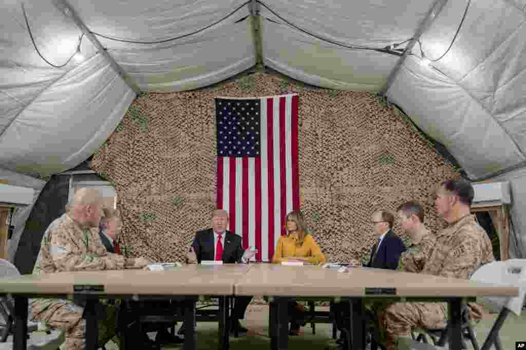 El presidente Donald Trump, acompañado por el asesor de seguridad nacional John Bolton, tercero de la izquierda, la primera dama Melania Trump, cuarta de la derecha, el embajador de Estados Unidos en Irak, Doug Silliman, tercero de la derecha, y líder militar de alto rango. 