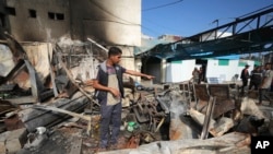 Mohamed al-Dalu sedang menunggu di lokasi tempat saudaranya, Shaban, tewas dalam kebakaran setelah serangan Israel menghantam area tenda di halaman rumah sakit Al Aqsa Martyrs di Deir al-Balah, Jalur Gaza, 16 Oktober 2024. (Foto: AP)