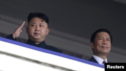 FILE - North Korean leader Kim Jong-un (L) salutes next to China's Vice President Li Yuanchao during a parade in Pyongyang July 27, 2013.