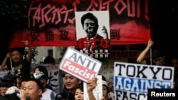 Protesters holding placards shout slogans at a rally against Japan's Prime Minister Shinzo Abe's push to expand Japan's military role in front of Abe's official residence in Tokyo, June 30, 2014.