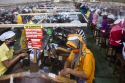 Buruh melinting tembakau di terminal kerja mereka, dipisahkan oleh penutup plastik sebagai bagian dari tindakan di tengah pandemi virus Covid-19, di pabrik rokok Gudang Baru di Malang, Jawa Timur, pada 11 Juli 2020. (Foto: AMAN ROCHMAN / AFP)