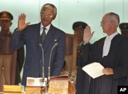 In this May 10, 1994, file photo, Nelson Mandela, left, takes the oath of office in Pretoria, South Africa, to become the country's first black President.