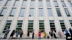 FILE - Reporters and spectators wait in line outside Brooklyn federal court, in New York, for opening statements in R&B star R. Kelly's long-anticipated federal trial, Aug. 18, 2021.