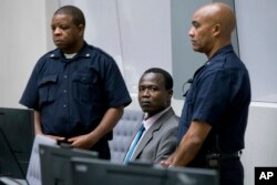 FILE - Dominic Ongwen, center, a senior commander in the Lord's Resistance Army, whose fugitive leader Kony is one of the world's most-wanted war crimes suspects, sits in the court room of the International Court in The Hague, Netherlands, Dec. 6, 2016.