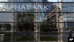 A pedestrian enters an Alpha Bank building in Athens, October 1, 2012.