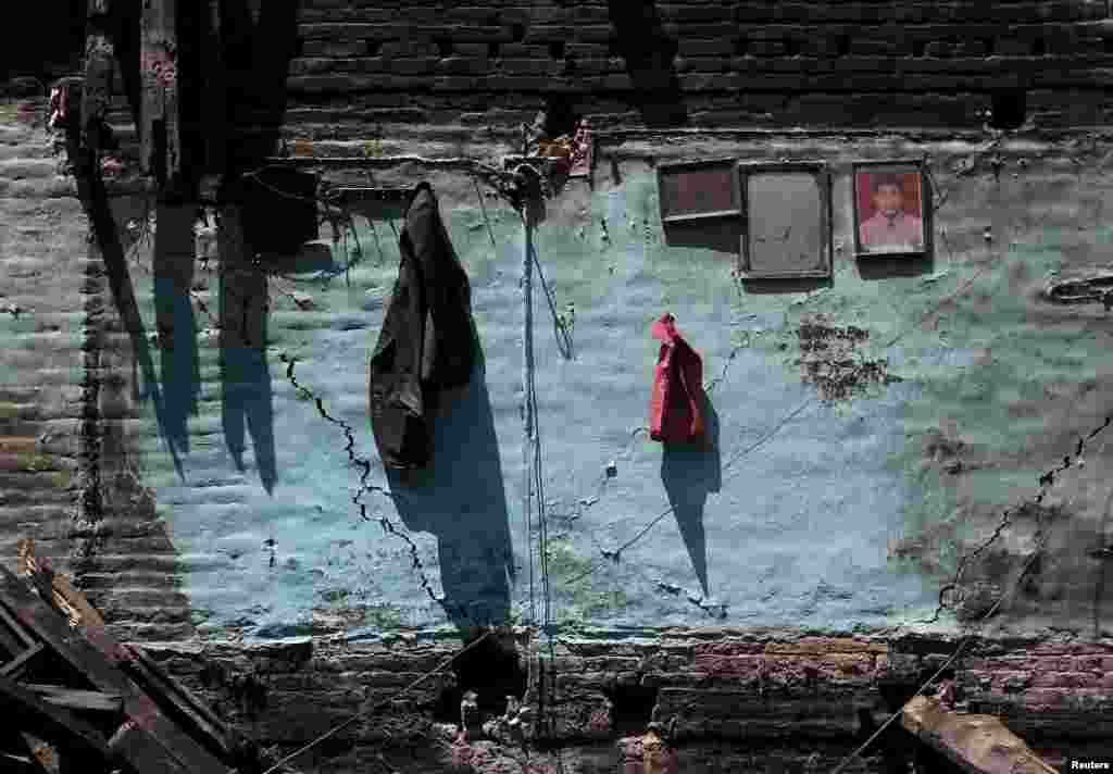A coat and a framed portrait are seen hanging on a cracked wall of a damaged house after an earthquake in Bhaktapur, Nepal.