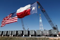 American and Texas flags fly from the tops of cranes near an oil rig by the site where President Donald Trump delivered remarks about American energy production during a visit to Midland, Texas, July 29, 2020.