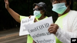 Annie Gordon, left, and Jenny Clark, rally for protection from evictions Saturday, June 27, 2020, in the Mattapan neighborhood of Boston. Massachusetts' tenant eviction moratorium is slated to expire in mid-August. (AP Photo/Michael Dwyer)