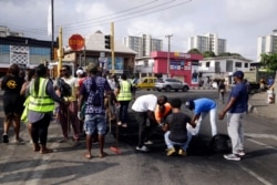 Volunteers sweep burned tire on the roads in Lagos, Oct. 24, 2020. Nigeria's president says 51 civilians have been killed in unrest following days of peaceful protests over police abuses, and he blames "hooliganism" for the violence.