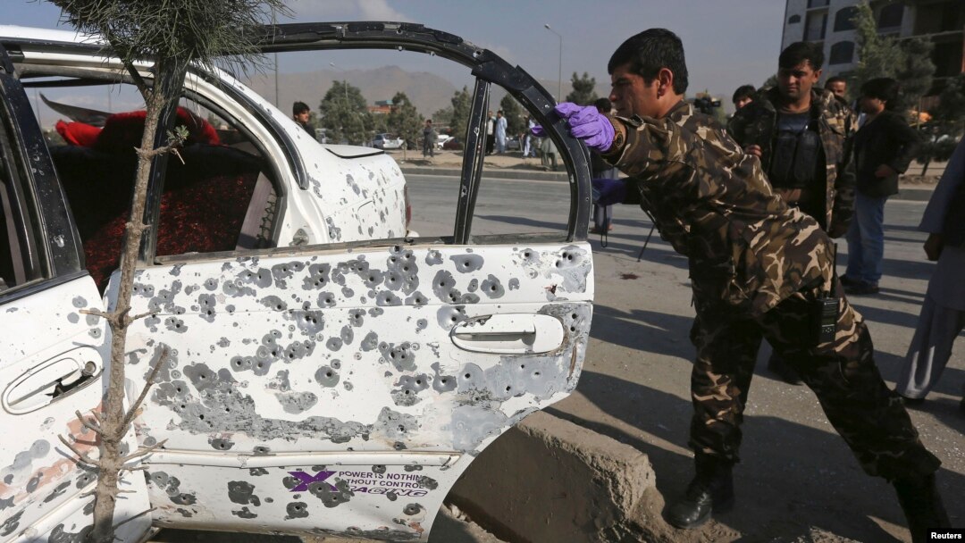 Seorang anggota pasukan keamanan Afghanistan memeriksa mobil yang hancur akibat ledakan bom di Kabul (14/10)
