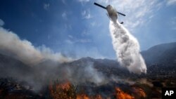 A helicopter drops water over a wildfire in Cabazon, California, August 8, 2013. About 1,500 people have fled and three are injured as a wildfire in the Southern California mountains quickly spreads. 