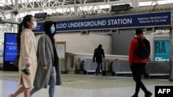 Orang-orang memakai masker wajah, yang direkomendasikan untuk dipakai di angkutan umum, di stasiun Waterloo di London, 11 Mei 2020. (Foto: AFP)