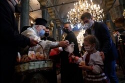 El patriarca ecuménico Bartolomé I (izq.), líder espiritual de los cristianos ortodoxos del mundo, reparte regalos a fieles ucranianos tras el servicio de Pascua en la Catedral de San Jorge, en Estambul, el domingo 2 de mayo de 2021.