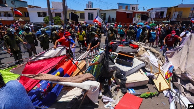 Manifestantes destruyen tiendas de campaña y artículos pertenecientes a migrantes venezolanos y colombianos durante una marcha contra la migración ilegal en Iquique, Chile, el domingo 30 de enero de 2022.