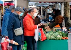 Orang-orang mengenakan masker saat berbelanja di pasar di Saint Jean de Luz, barat daya Prancis, Jumat, 14 Januari 2022.