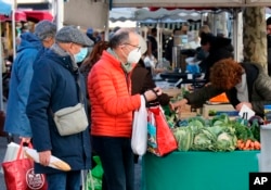 Orang-orang mengenakan masker saat berbelanja di pasar di Saint Jean de Luz, barat daya Prancis, Jumat, 14 Januari 2022.