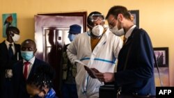 Zimbabwean journalist and documentary film maker Hopewell Chin'ono (2nd L) consults with his lawyers Beatrice Mtetwa (L) and Doug Coltart (R) while police search his office in Harare on July 21, 2020. 