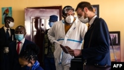 Zimbabwean journalist and documentary film maker Hopewell Chin'ono (2nd L) consults with his lawyers Beatrice Mtetwa (L) and Doug Coltart (R) while police search his office in Harare on July 21, 2020. 