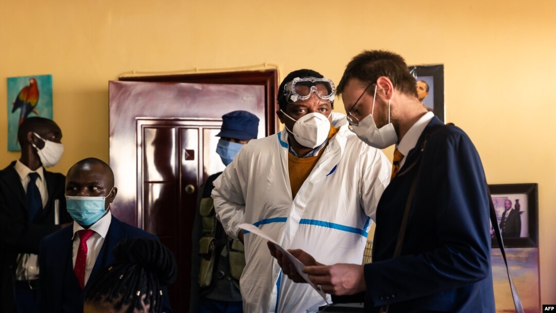 Zimbabwean journalist and documentary film maker Hopewell Chin'ono (2nd L) consults with his lawyers Beatrice Mtetwa (L) and Doug Coltart (R) while police search his office in Harare on July 21, 2020. 