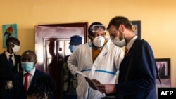 Zimbabwean journalist and documentary film maker Hopewell Chin'ono (2nd L) consults with his lawyers Beatrice Mtetwa (L) and Doug Coltart (R) while police search his office in Harare on July 21, 2020. 