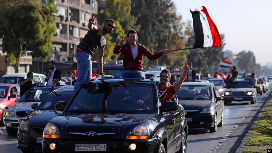 Syrian government supporters wave national flags and chant slogans against U.S. President Trump during demonstrations following a wave of U.S., British and French military strikes to punish President Bashar Assad for suspected chemical attack against civi