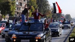 Syrian government supporters wave national flags and chant slogans against U.S. President Trump during demonstrations following a wave of U.S., British and French military strikes to punish President Bashar Assad for suspected chemical attack against civi