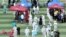 Medical workers in protective suits help people lining up inside a sports center for nucleic acid tests, following new cases of coronavirus disease (COVID-19) in Beijing, China, June 15, 2020.