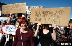 People hold banners as they protest next to the Brandenburg Gate, beside the U.S. embassy, against the U.S. withdrawal from the Paris climate change deal, in Berlin, Germany, June 2, 2017.