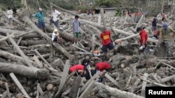 Tim SAR dan relawan mengangkat mayat korban topan Bopha yang tertindih tumpukan kayu yang terbawa arus banjir bandang di kota New Bataan, Lembah Compostela,Filipina (7/12).