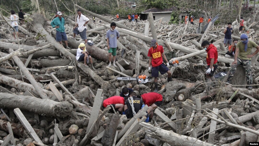 Tim SAR dan relawan mengangkat mayat korban topan Bopha yang tertindih tumpukan kayu yang terbawa arus banjir bandang di kota New Bataan, Lembah Compostela,Filipina (7/12).