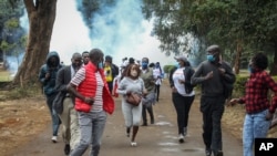 Demonstrators run from teargas fired by police at a protest against alleged corruption, including the theft of supplies for the fight against the coronavirus, at Uhuru Park in downtown Nairobi, Kenya, Aug. 21, 2020.