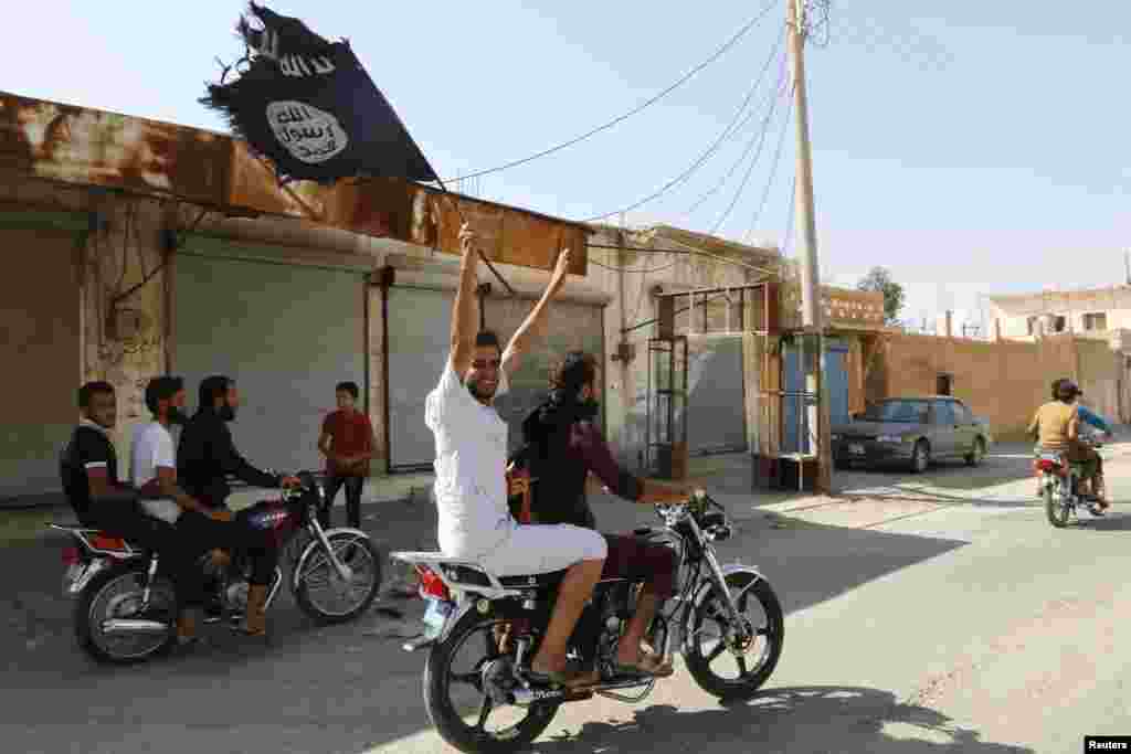 Warga Tabqa berkeliling kota dengan sepeda motor, mengibar-kibarkan bendera Islamis untuk merayakan perebutan pangkalan udara Tabqa oleh militan Negara Islam, dekat Raqqa, Suriah (24/8).