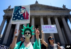 Counter demonstrators opposing a group who gathered across the street to protest against Islamic law, hold signs, June 10, 2017, in New York.