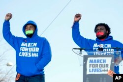 Alex King, right, and D'Angelo McDade, left, both graduating seniors at North Lawndale College Prep High School in Chicago, raise their fists in the air as they arrive to speak during the "March for Our Lives" rally in Washington, March 24, 2018. Both are Peace Warriors at their school.