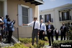 U.S. President Barack Obama, with New Orleans Mayor Mitch Landrieu at his back, chats with city residents in an area reconstructed after Hurricane Katrina, Aug. 27, 2015.