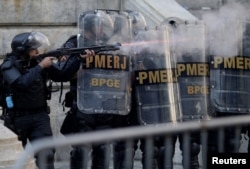 A riot policeman fires rubber bullets during clashes with demonstrators outside the Rio de Janeiro State Assembly in Rio de Janeiro, Brazil, Nov. 17, 2017.