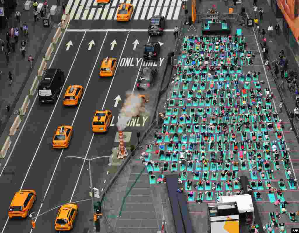 People take part in the 15th annual Times Square yoga event celebrating the Summer Solstice, the longest day of the year, during classes in the middle of Times Square in New York. 