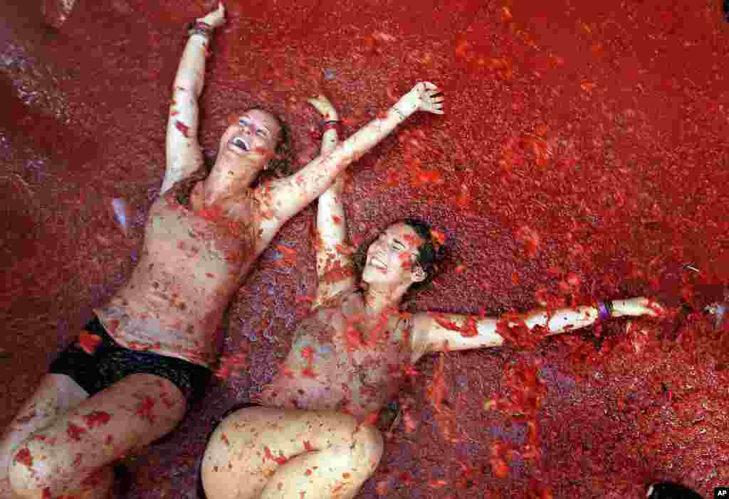 Two woman lie in a puddle of squashed tomatoes during the annual &quot;tomatina&quot; tomato fight fiesta, in the village of Bunol, 50 kilometers outside Valencia, Spain.