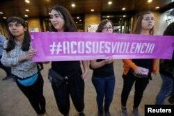 FILE - Members of feminist organizations hold a placard, which reads "Harassment is violence" during a rally against sexual harassment and gender violence in Santiago, Chile, Oct. 24, 2017.