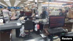 Customers queue in 'Rost' supermarket in Kharkiv, Ukraine, June 27, 2017 in this picture obtained from social media. An infected computer in the foreground shows a ransom message on the screen.