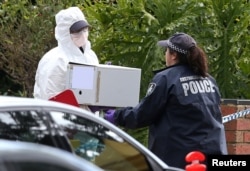 Australian police carry a box from the home of gunman Yacqub Khayre, who was shot dead by police on June 5, 2017, after he shot a man dead and held a woman hostage in the Melbourne suburb of Roxburgh Park in Australia.