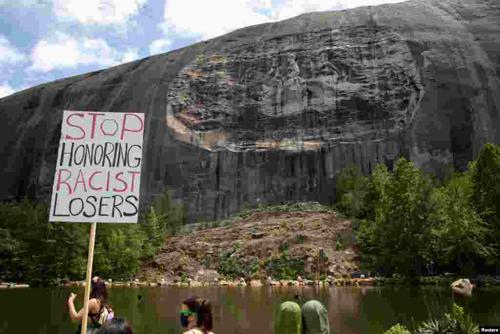 A protest sign is held up in front of the Confederate Monument carved into granite at Stone Mountain Park in Stone Mountain, Georgia, June 16, 2020.
