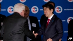 Japanese Prime Minister Shinzo Abe is greeted by U.S. Chamber of Commerce President and CEO Tom Donohue, left, as he arrives at a meeting at chamber offices in Washington, April 29, 2015.