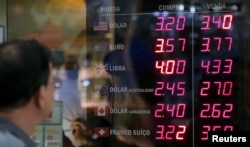 A man observes a board showing the Brazilian Real-U.S. dollar and several other foreign currencies exchange rates in Rio de Janeiro, Brazil, Nov. 9, 2016.