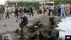 People and security forces inspect the scene of a car bomb attack in Basra, 340 miles (550 kilometers) southeast of Baghdad, Iraq, July 2, 2013. 